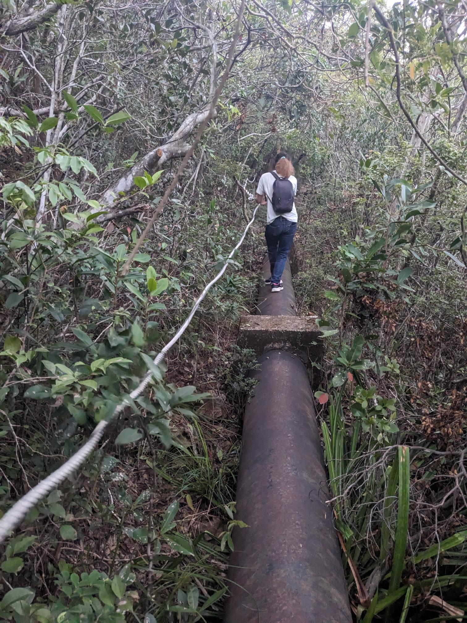 A person balances over a pipe, holding onto a rope. A person balances over a pipe, holding onto a rope.