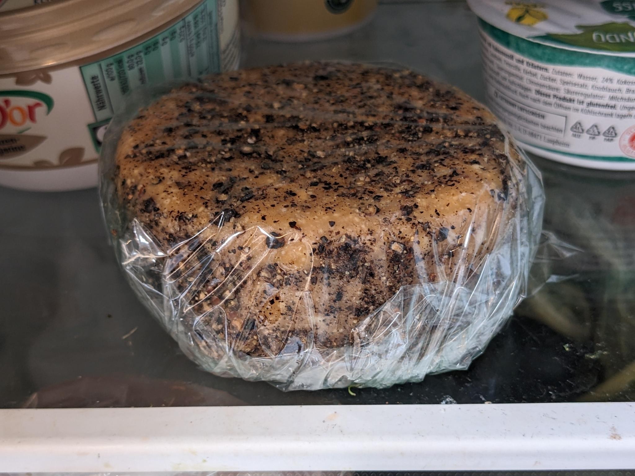 The resulting cheese in plastic wrap in the fridge.