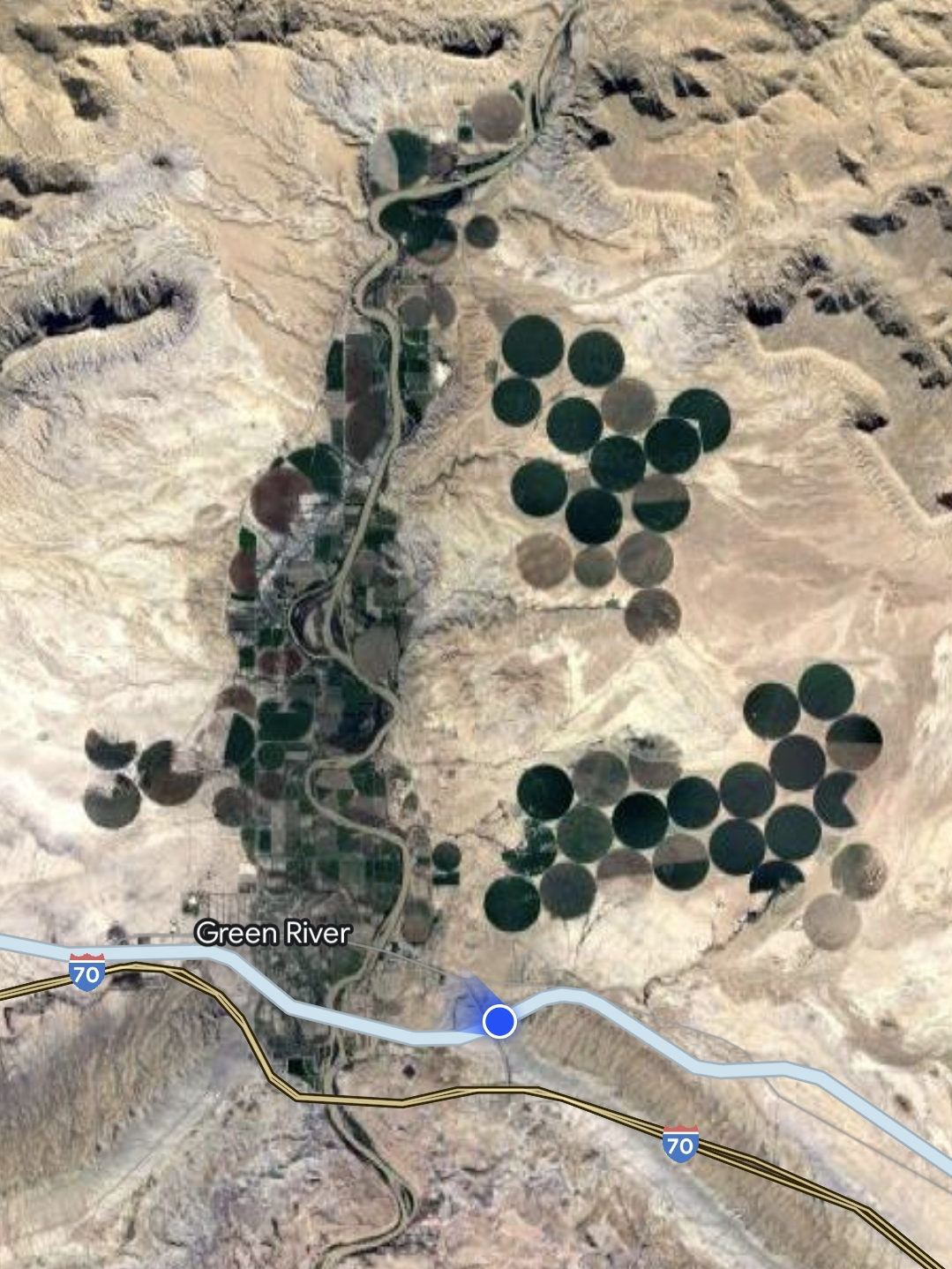 Next to a town, in a satellite image, there are multiple big dark circles visible. Some have patterns in them.