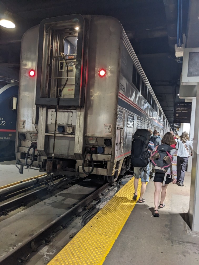 A two-storey metal train. People are walking towards it.