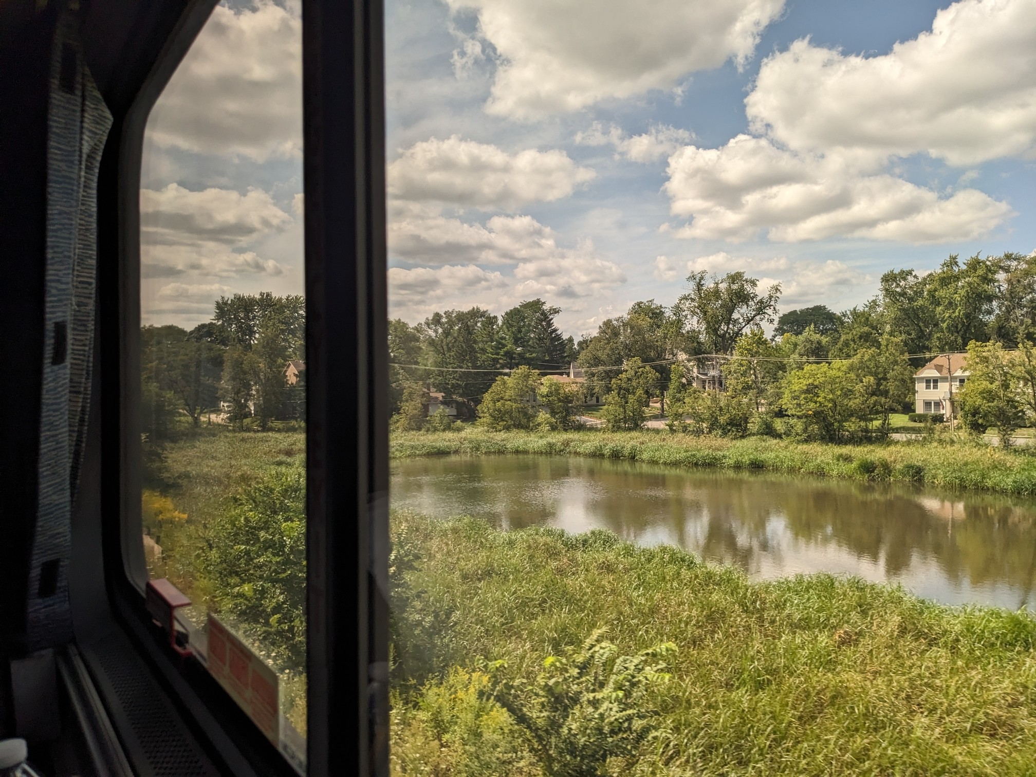 House by a lake outside a train window.