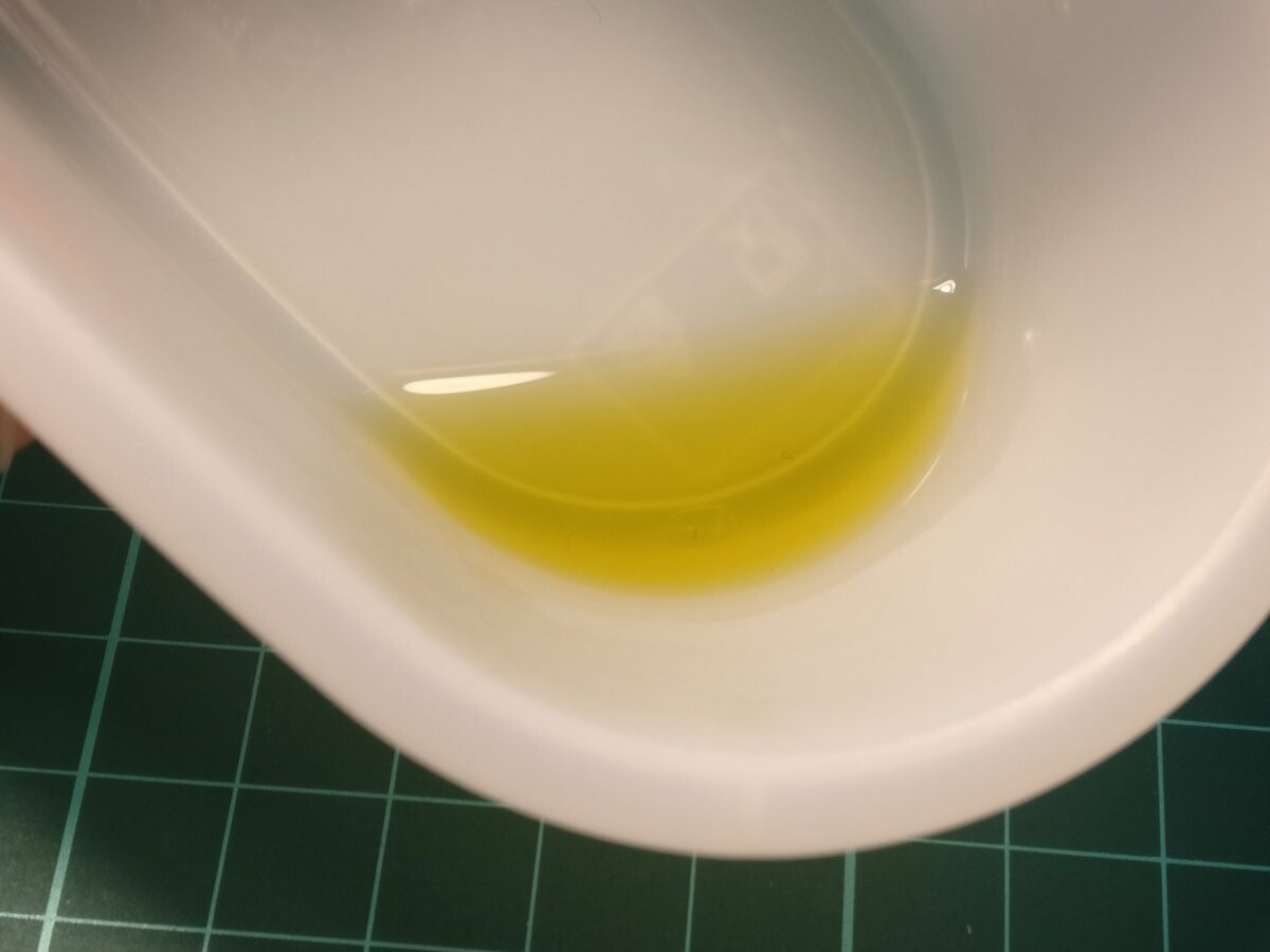 A little bit of yellow oil in a plastic container.