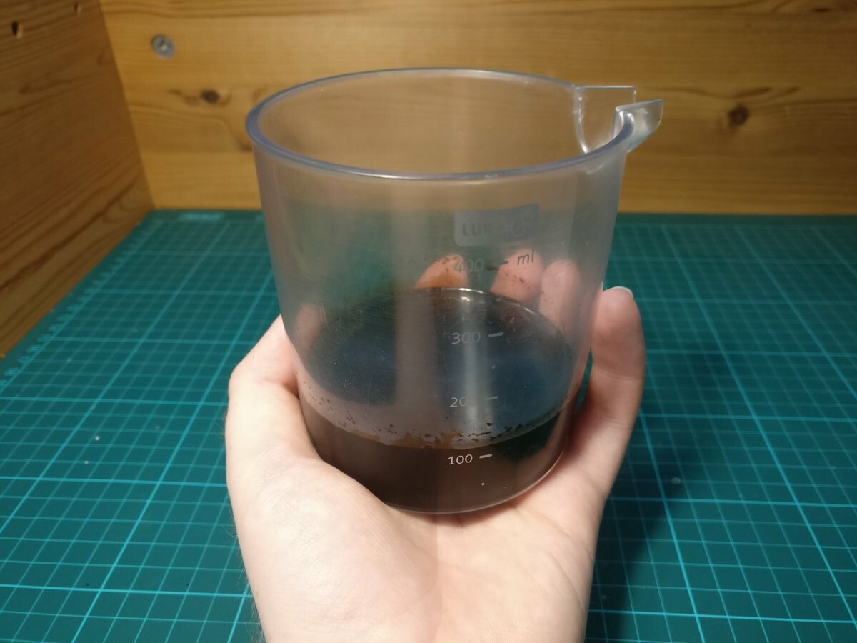 I'm holding a plastic container containing some brown liquid.