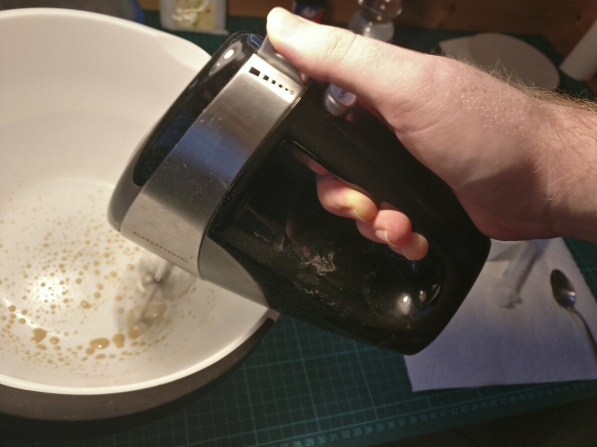 I'm using a hand mixer in a big plastic bowl on a bit of milky brown substance.