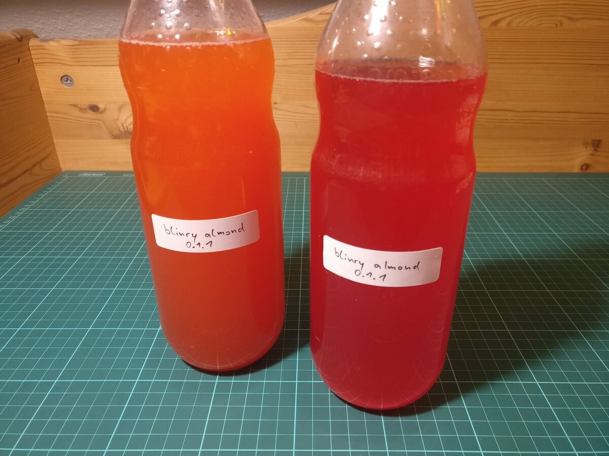 Two bottles of red-orange soft drink concentrate.