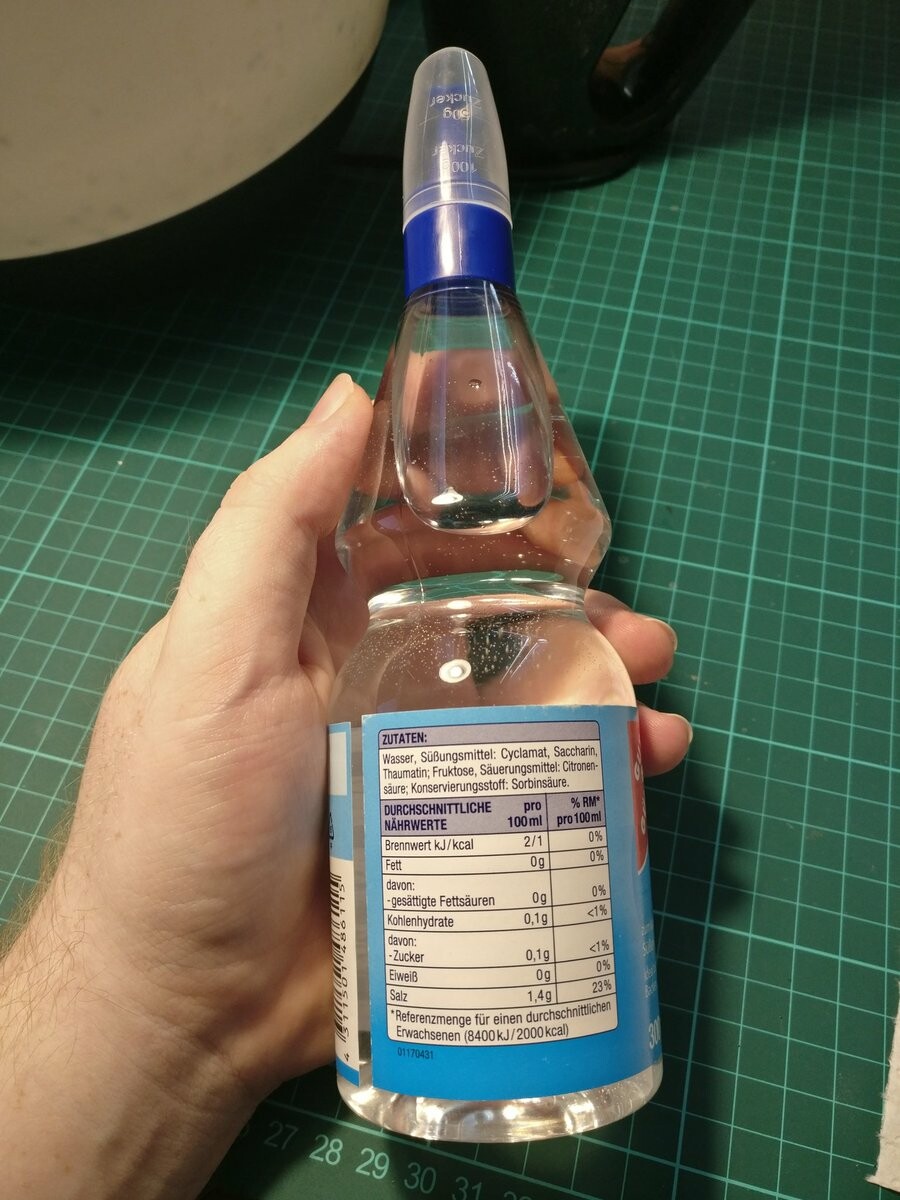 I'm holding a bottle of transparent liquid sweetener.