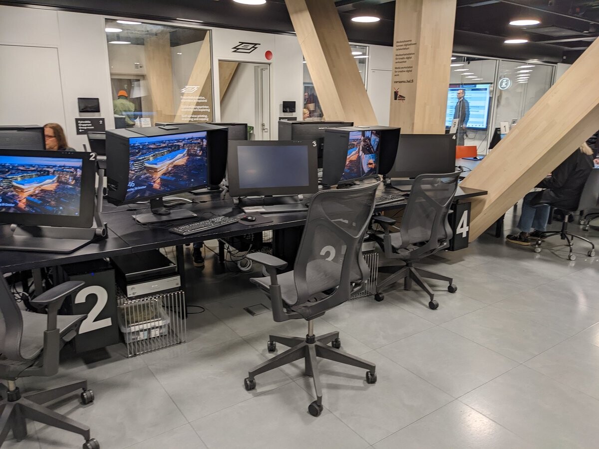 Black tables with comfortable office chairs, and monitors that have shades so you'll get less reflections.