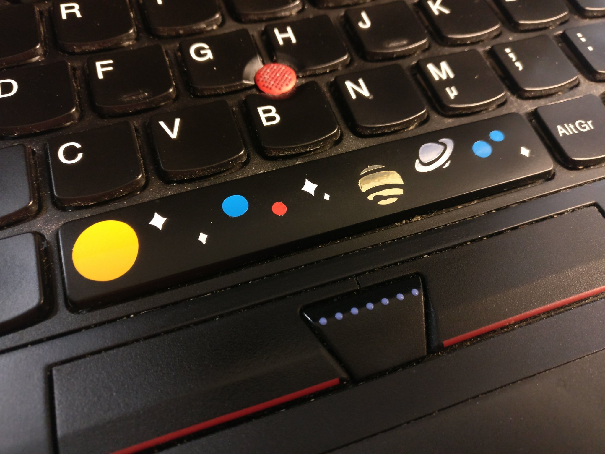 Space bar on a keyboard, with some tiny stars and planets glued on it